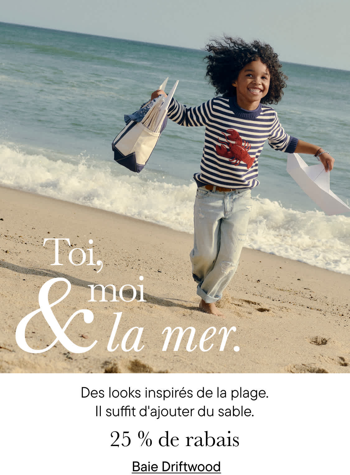 Une personne souriante, vêtue d'une chemise à rayures, marche le long d'une plage de sable fin, l'océan en arrière-plan, tenant un sac sur lequel on peut lire « Toi, moi et la mer ».