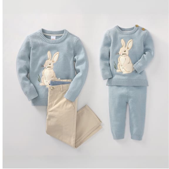 L'image présente un ensemble pull et pantalon gris, orné chacun d'un grand lapin couleur crème. Les vêtements sont disposés sur un fond blanc uni, créant ainsi une composition visuelle minimaliste et épurée.
