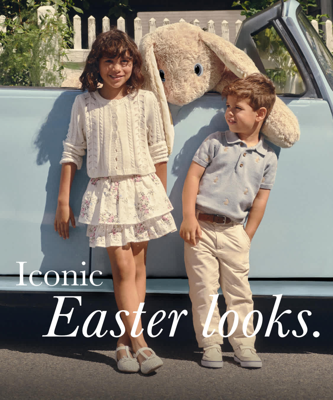 The image features a group of young people, likely a family, posing together in a casual outdoor setting. They are dressed in light, floral-patterned clothing and appear to be celebrating or enjoying a spring or Easter-themed event. The background includes a wooden fence and lush greenery, suggesting a pastoral or suburban setting.