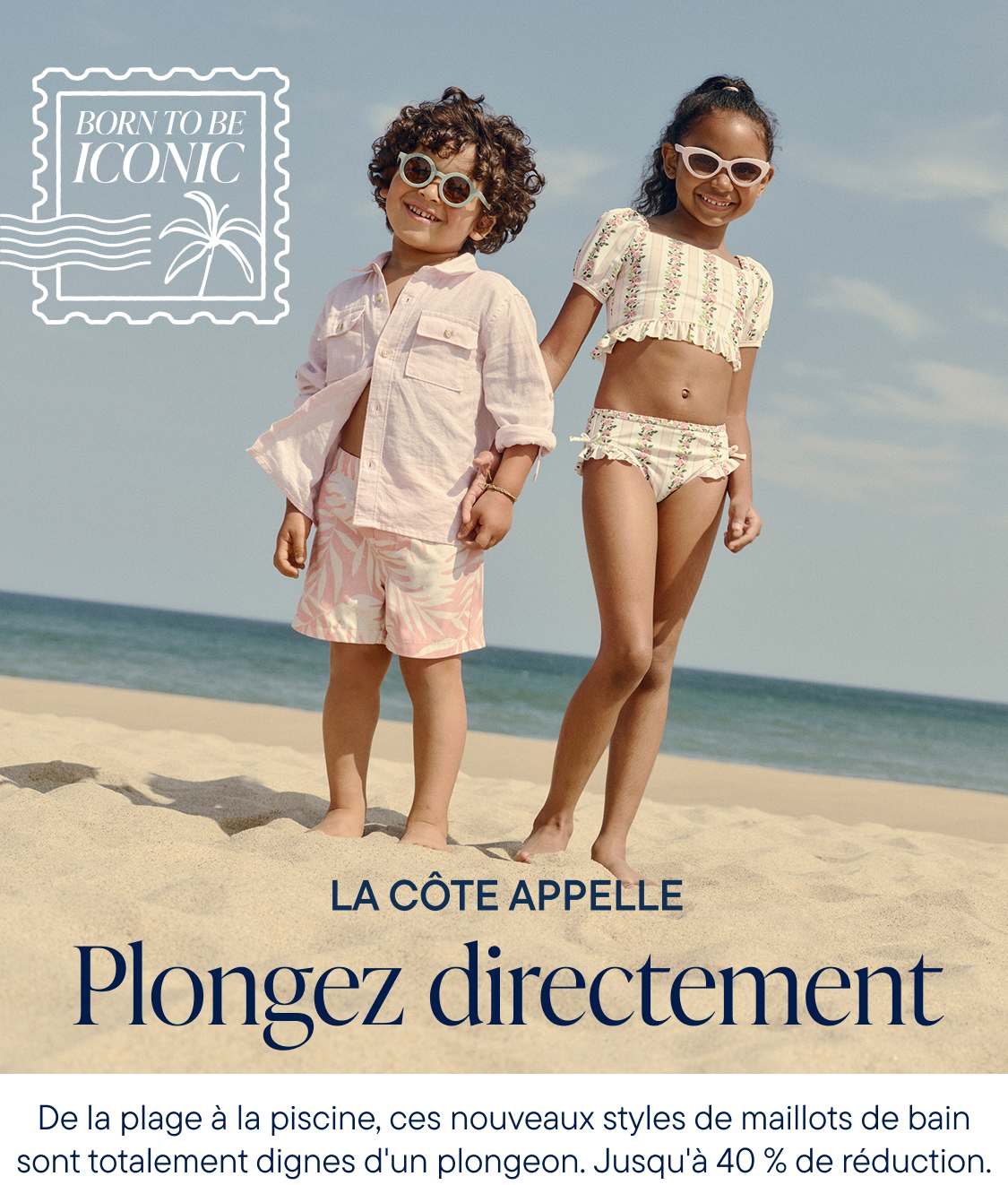 Deux jeunes femmes en tenues de plage élégantes se tiennent sur une plage de sable fin, avec l'océan et un ciel dégagé visibles en arrière-plan.