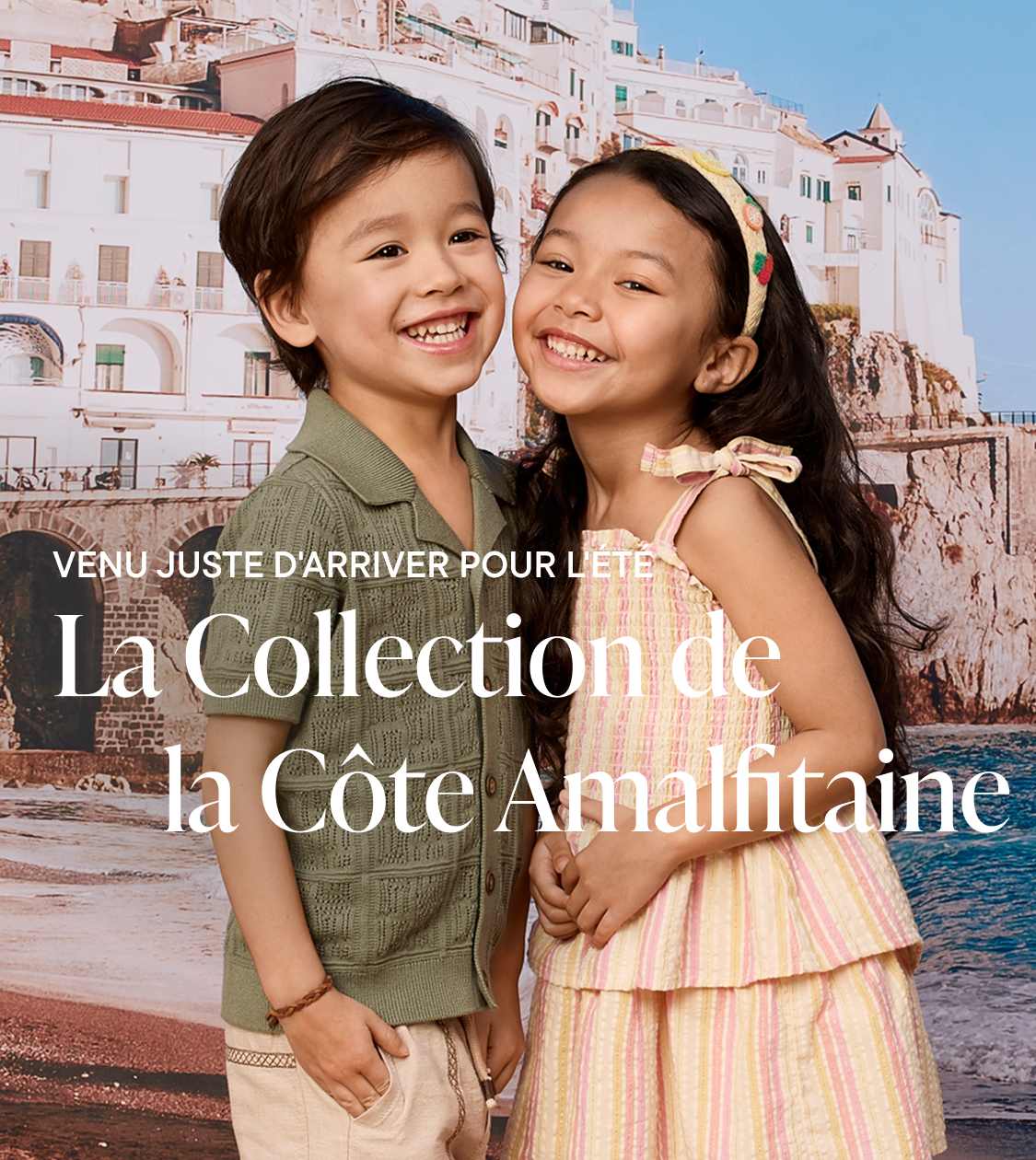 Deux enfants souriants, vêtus de vêtements d'été, se tiennent au premier plan, avec une pittoresque ville côtière italienne en arrière-plan.