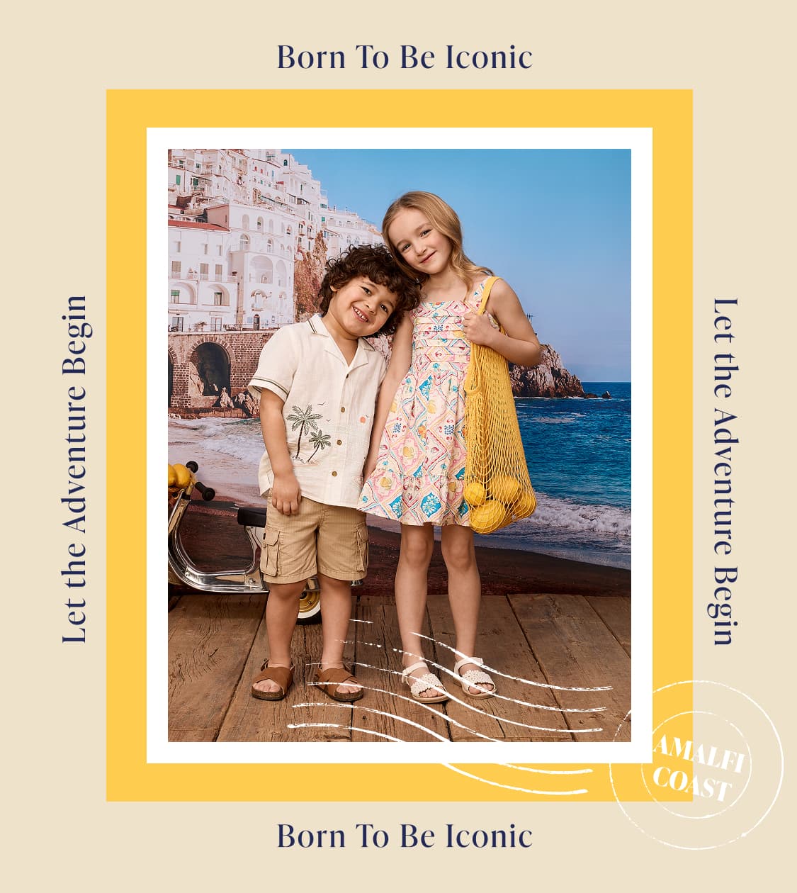 A young boy and girl stand smiling in front of a picturesque coastal town with buildings cascading down a cliffside.