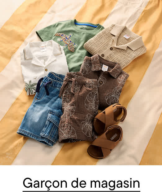 Une collection de vêtements d'été pour enfants, comprenant des chemises, des shorts et des sandales, est soigneusement disposée sur un fond rayé jaune et blanc.