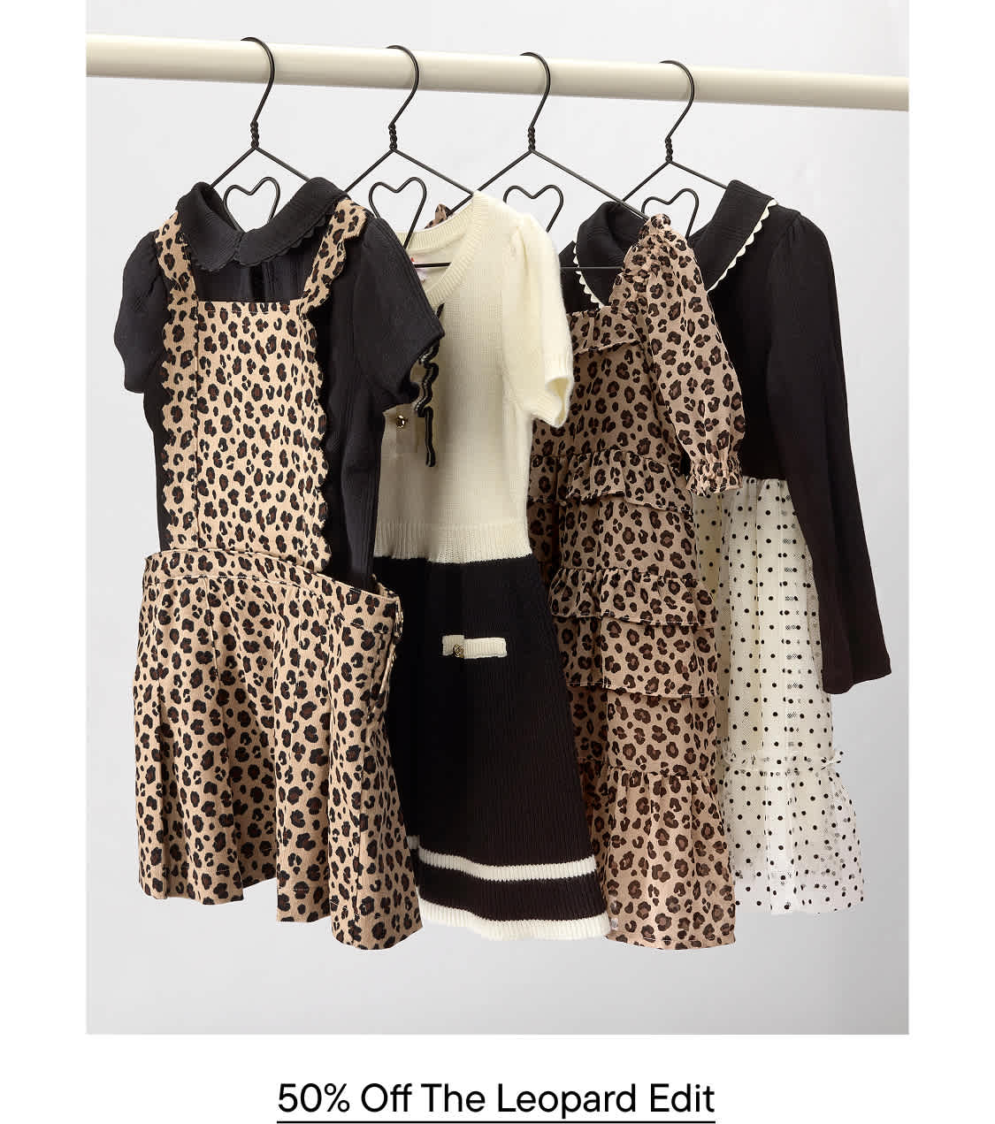 Four leopard-print and neutral-toned dresses hang from a white clothing rack against a plain white background.