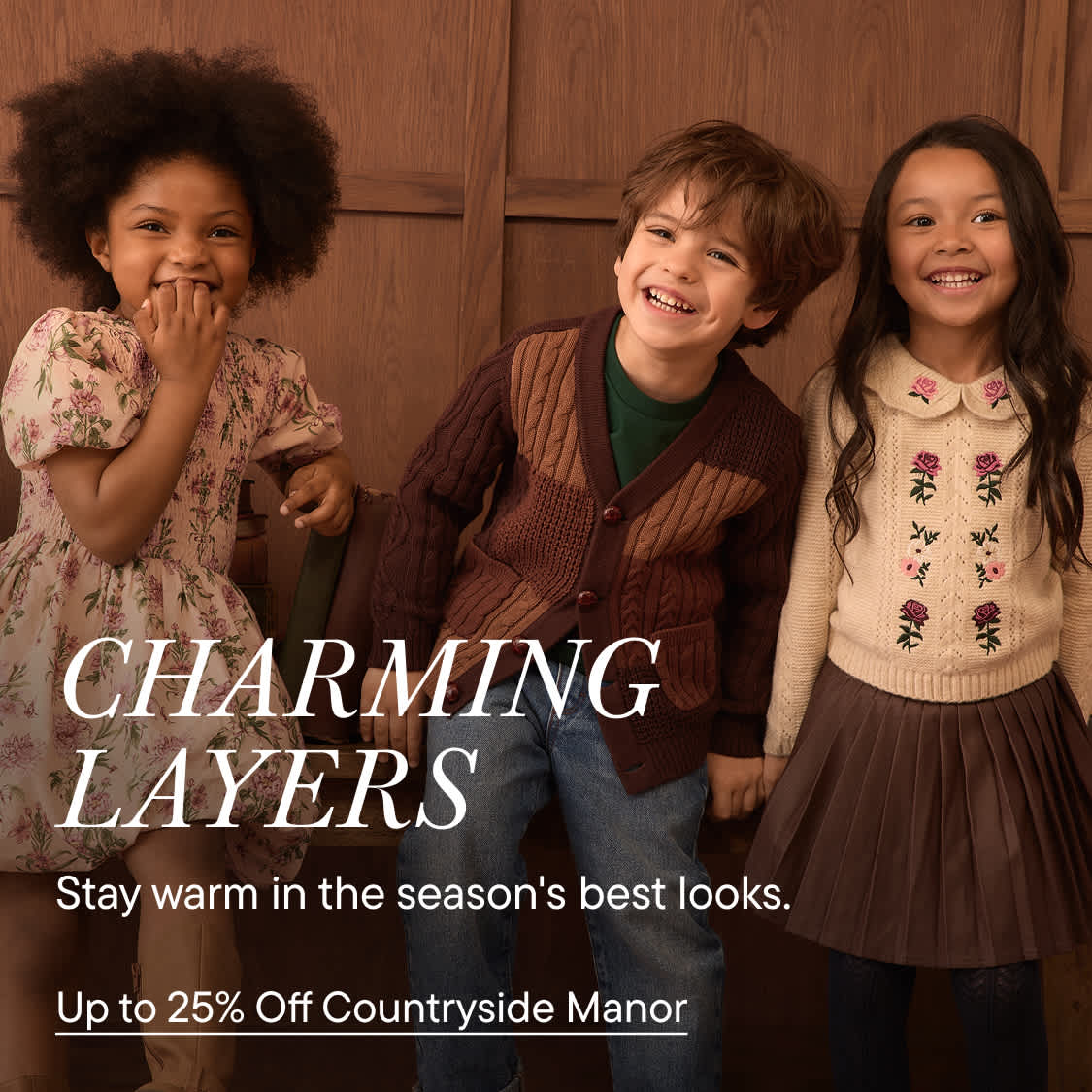 Three smiling children wearing autumn-style clothing stand in the foreground against a backdrop of brown wood paneling.