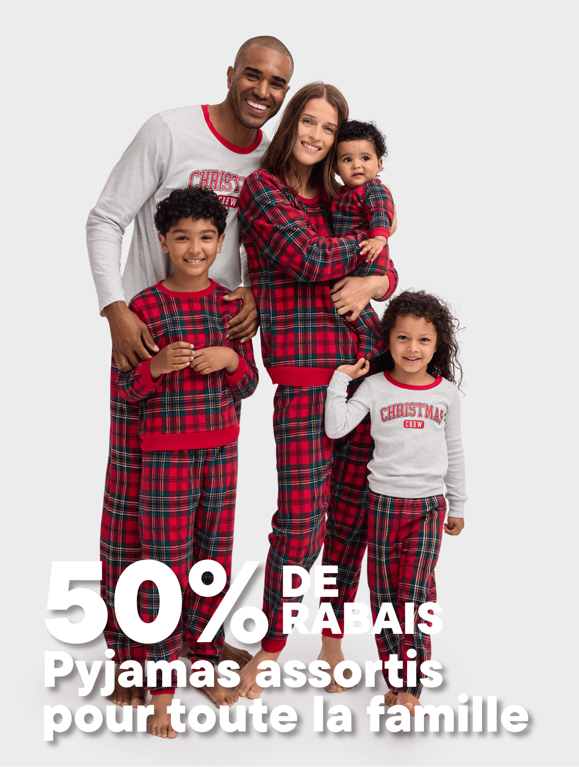 Une famille heureuse de quatre personnes, vêtues de pyjamas à carreaux assortis, se tient ensemble et sourit à la caméra sur un fond blanc uni, avec une promotion de 50 % de réduction sur les pyjamas familiaux assortis affichée bien en évidence.
