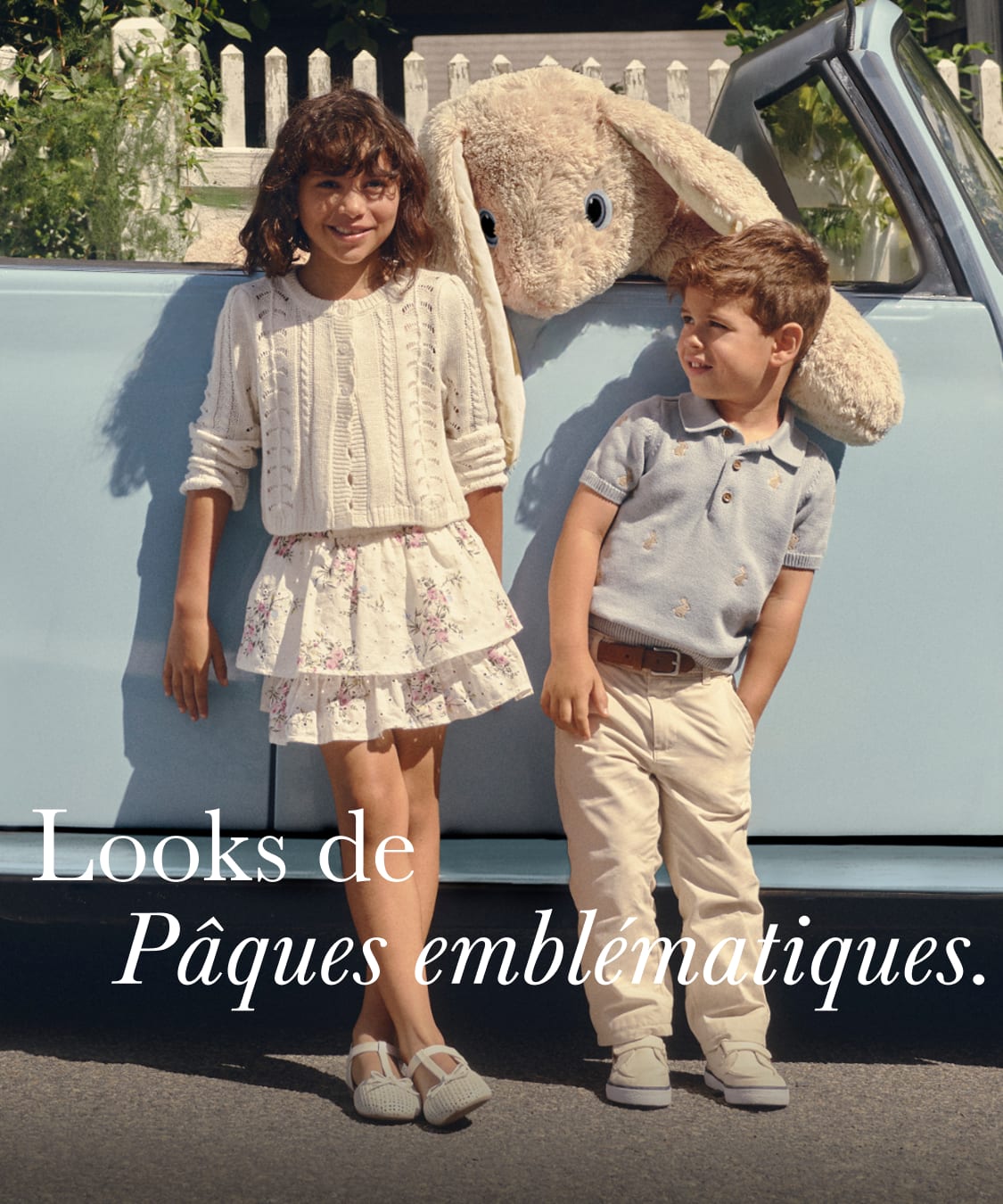 L'image montre un groupe de jeunes, probablement une famille, posant ensemble dans un cadre extérieur décontracté. Vêtus de vêtements clairs à motifs floraux, ils semblent célébrer ou profiter d'un événement printanier ou pascal. L'arrière-plan, composé d'une clôture en bois et d'une végétation luxuriante, évoque un cadre champêtre ou périurbain.