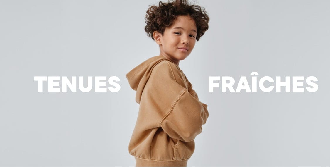 A young person with curly hair wearing a beige sweater stands against a plain white background with the text "FRESH FITS" prominently displayed.
