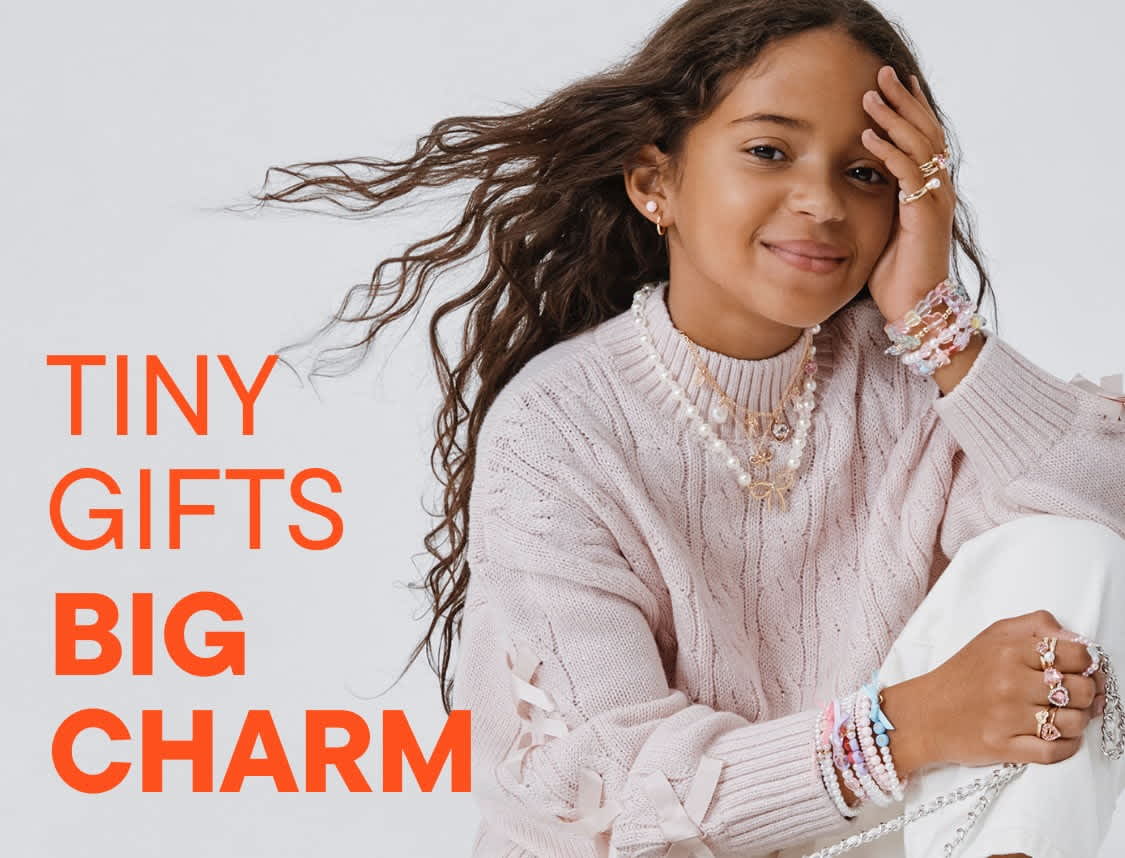 The image features three young women wearing casual, colorful clothing and posing together in front of a plain background. The women appear to be interacting with each other in a friendly and lively manner.
