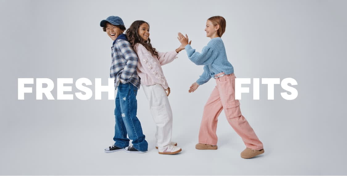The image features three young women wearing casual, colorful clothing and posing together in front of a plain background. The women appear to be interacting with each other in a friendly and lively manner.