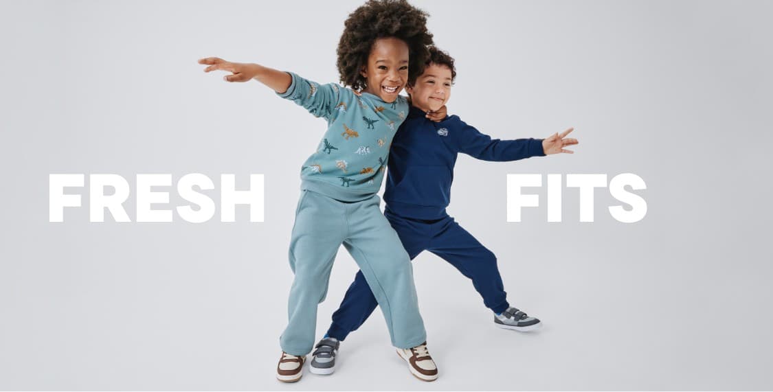 A young person with curly hair wearing a beige sweater stands against a plain white background with the text "FRESH FITS" prominently displayed.