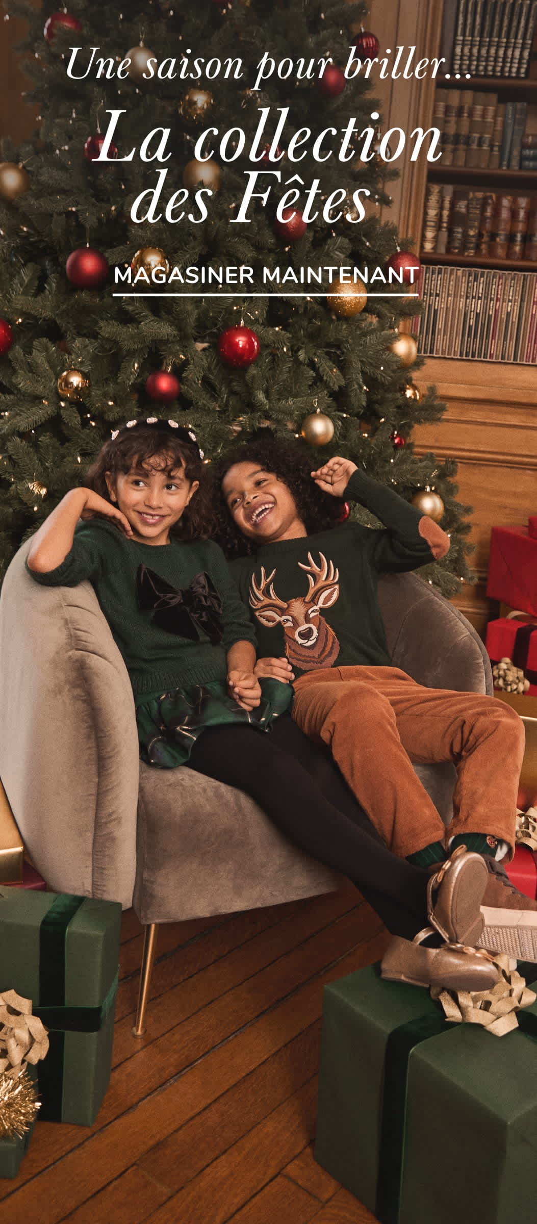 The image shows two people, a man and a woman, sitting on a couch in front of a Christmas tree with holiday decorations and a sign for "The Holiday Shop" in the background.