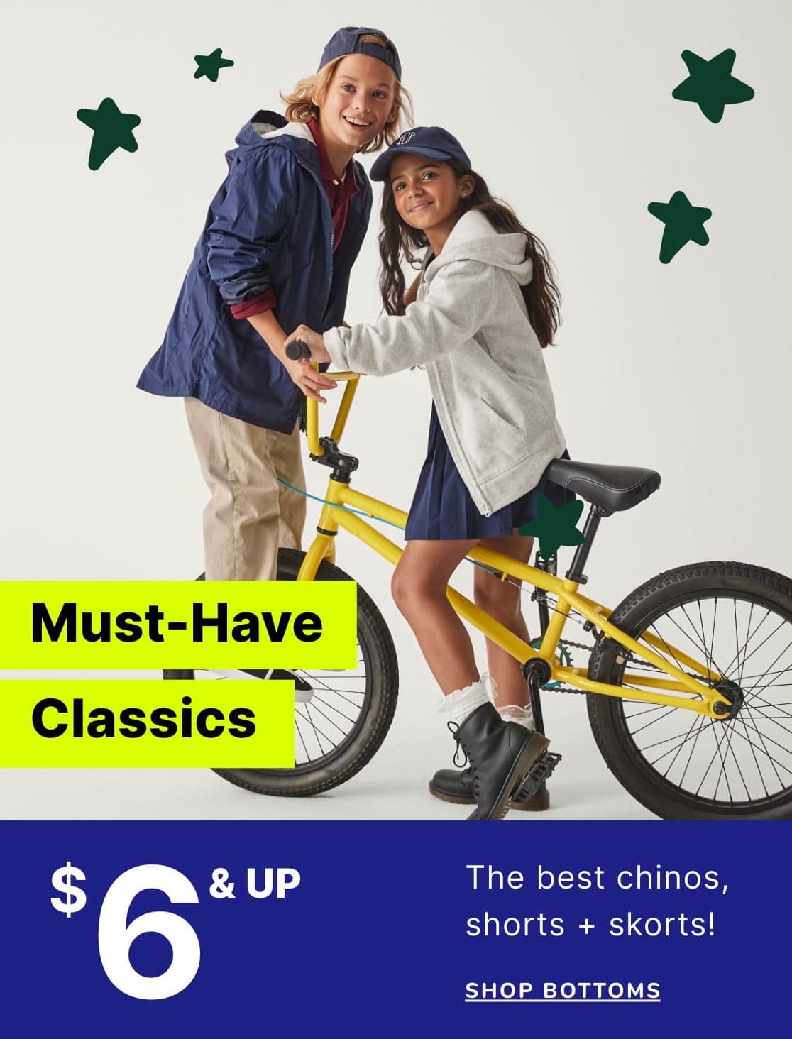 Two young people, a boy and a girl, are standing next to a bright yellow bicycle. The background features a plain white wall with green star-shaped shapes.