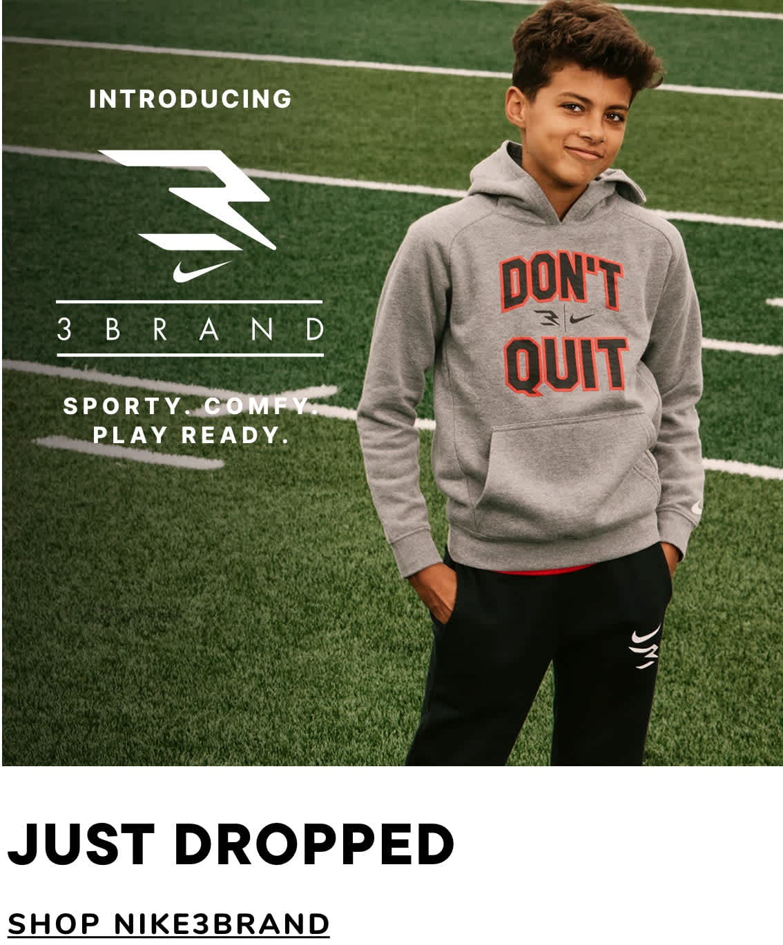 The image shows a young man wearing a gray hoodie with the text "Don't Quit" on it, standing in front of a green field and a Nike 3 Brand logo.