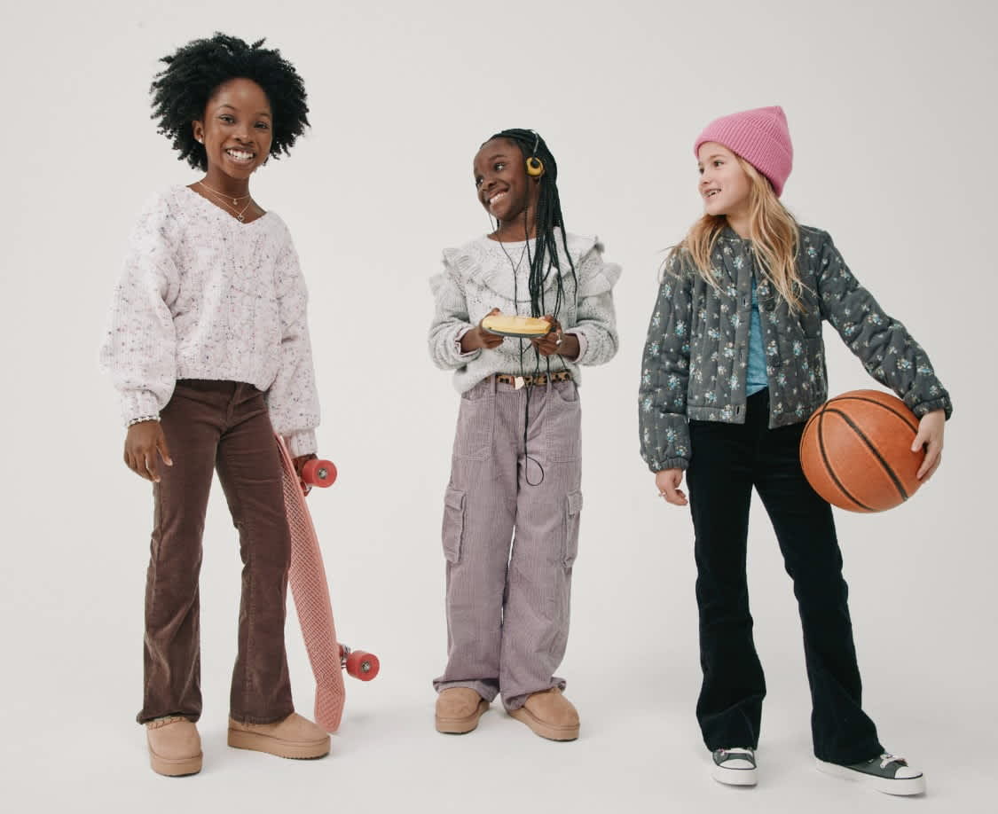 Trois jeunes femmes d'horizons divers se tiennent ensemble, chacune avec son style et sa personnalité uniques. L'image capture une scène vibrante et inclusive, mettant en valeur la diversité et l'individualité des personnes représentées.
