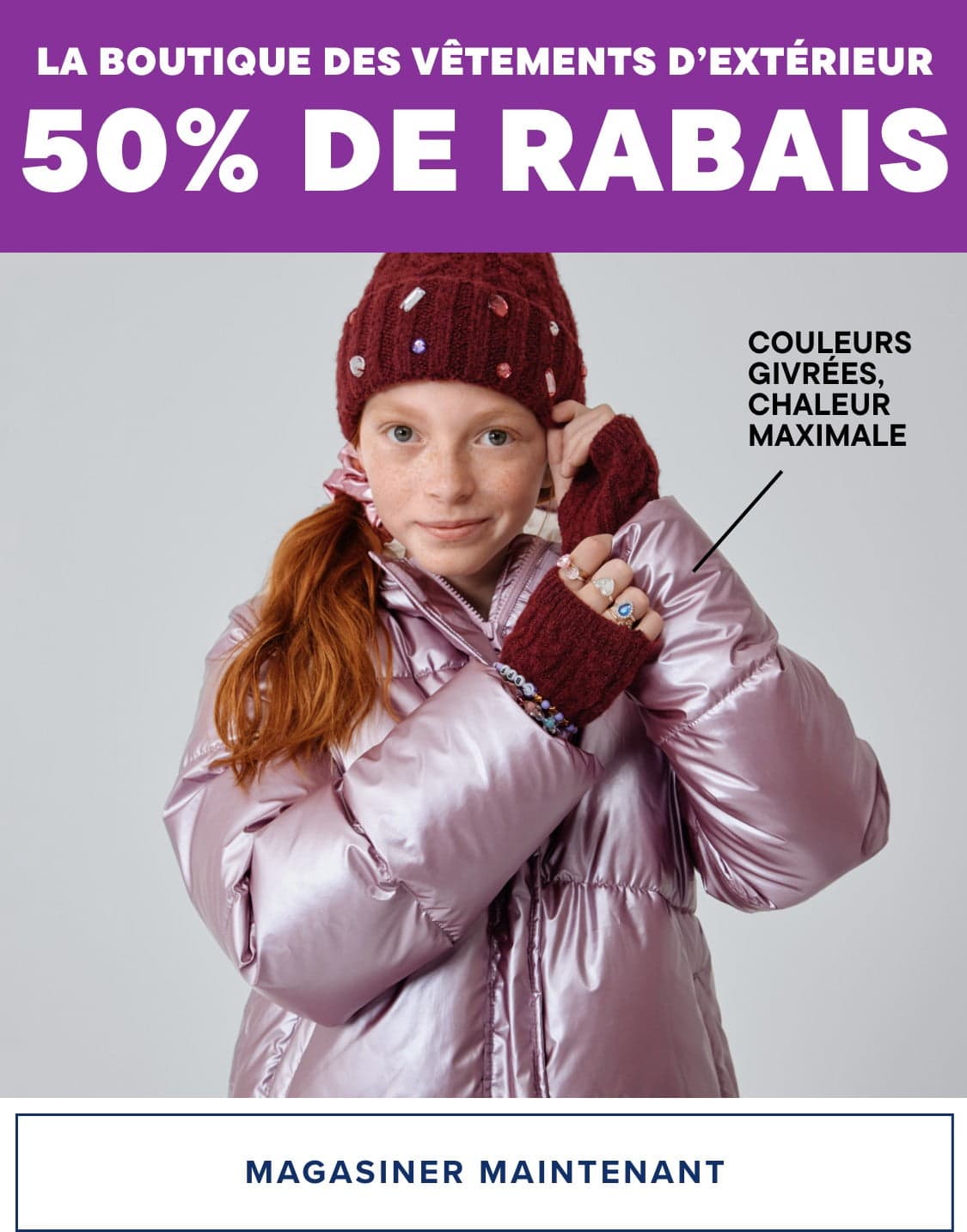 Une jeune femme portant un manteau d'hiver rose et un bonnet en tricot bordeaux se tient devant un fond blanc uni, avec un texte annonçant une vente à 50 % de réduction chez The Outerwear Shop.