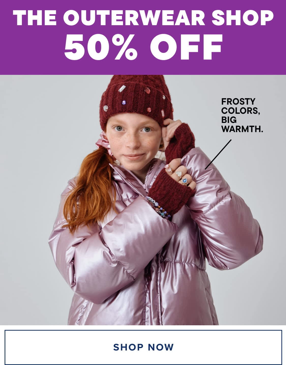 Una mujer joven de cabello rojo, que viste un abrigo de invierno rosado y un gorro de punto burdeos, se encuentra frente a un fondo blanco, con un texto que anuncia una oferta con un 50 % de descuento en The Outerwear Shop.