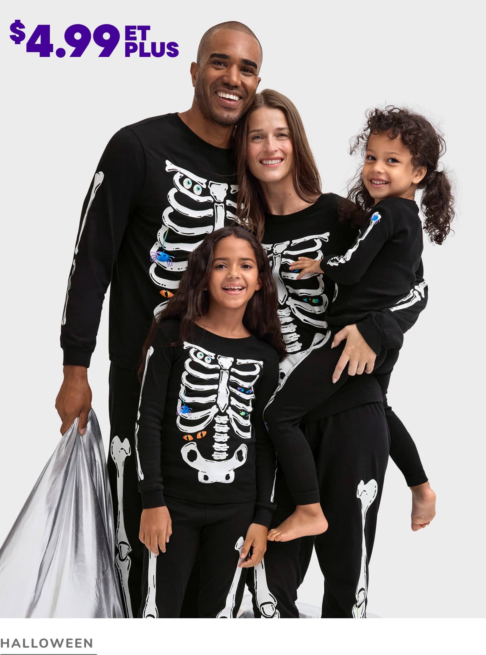 Une famille heureuse de quatre personnes, vêtues de costumes d'Halloween assortis sur le thème des squelettes, posant ensemble sur un fond blanc uni.