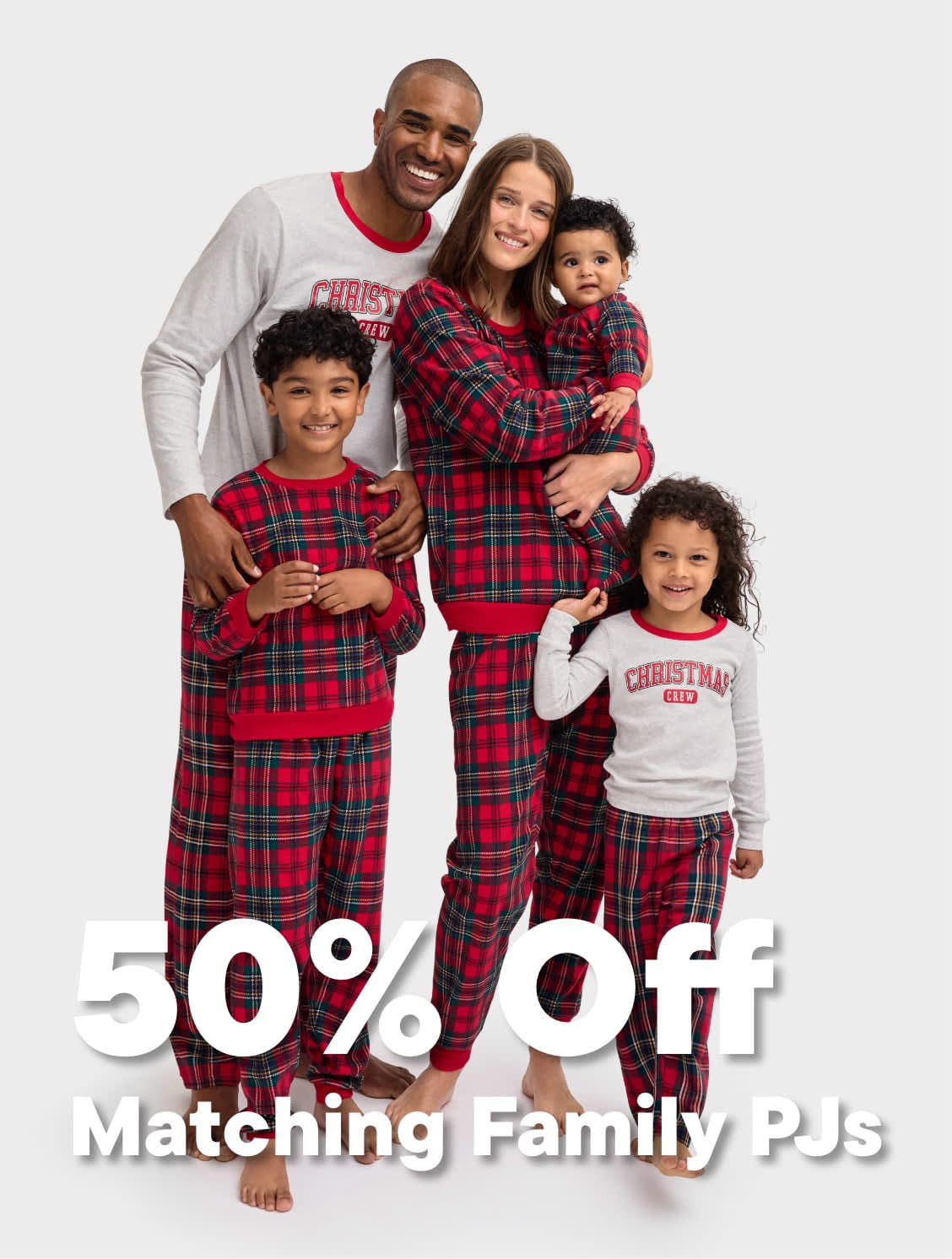 A happy family of four, dressed in matching plaid pajamas, stands together and smiles at the camera against a plain white background, with a 50% off promotion for matching family pajamas displayed prominently.
