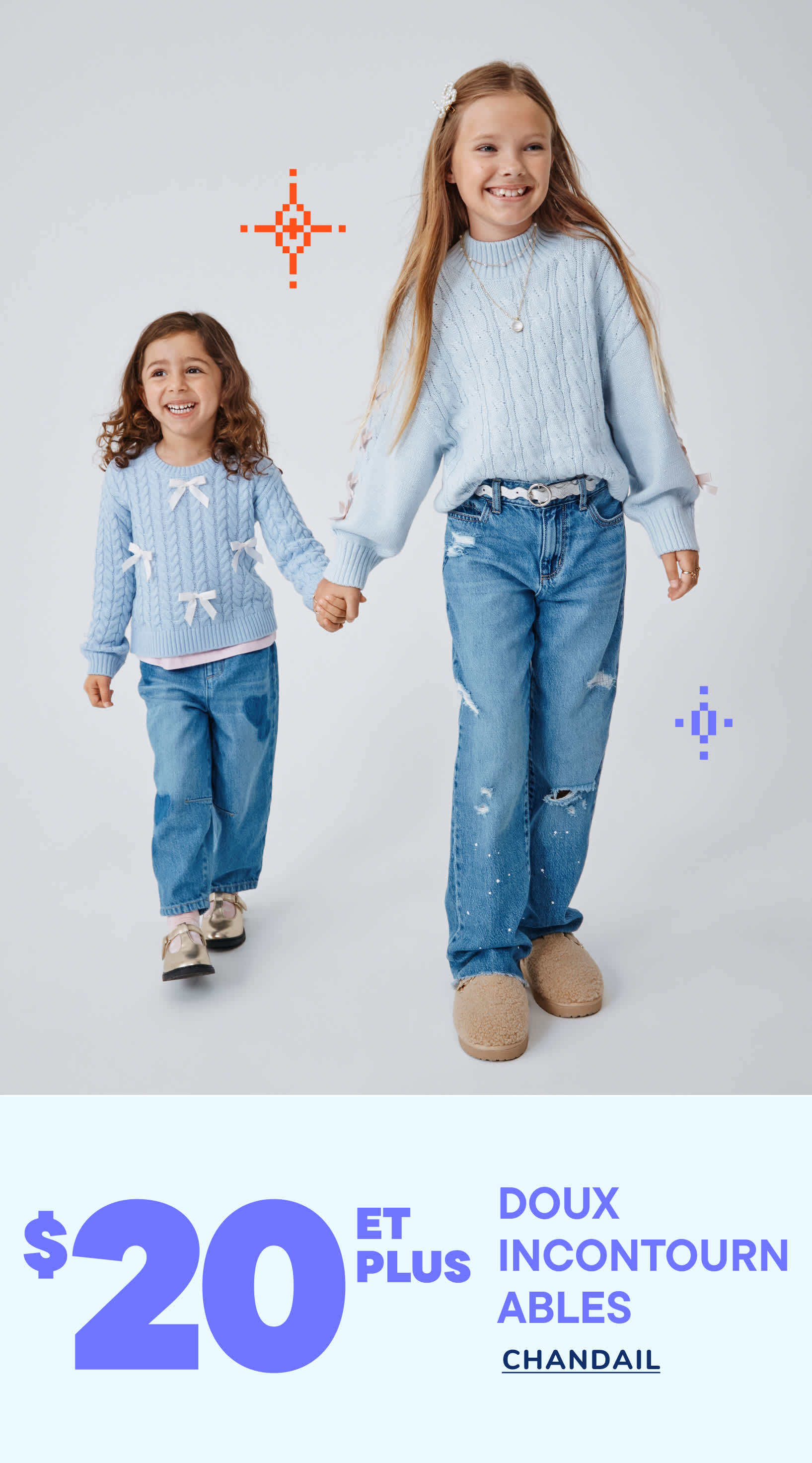 Deux jeunes filles aux longs cheveux bouclés se tiennent la main et sourient, vêtues de jeans et de pulls bleu clair. Le décor est un studio blanc uni.