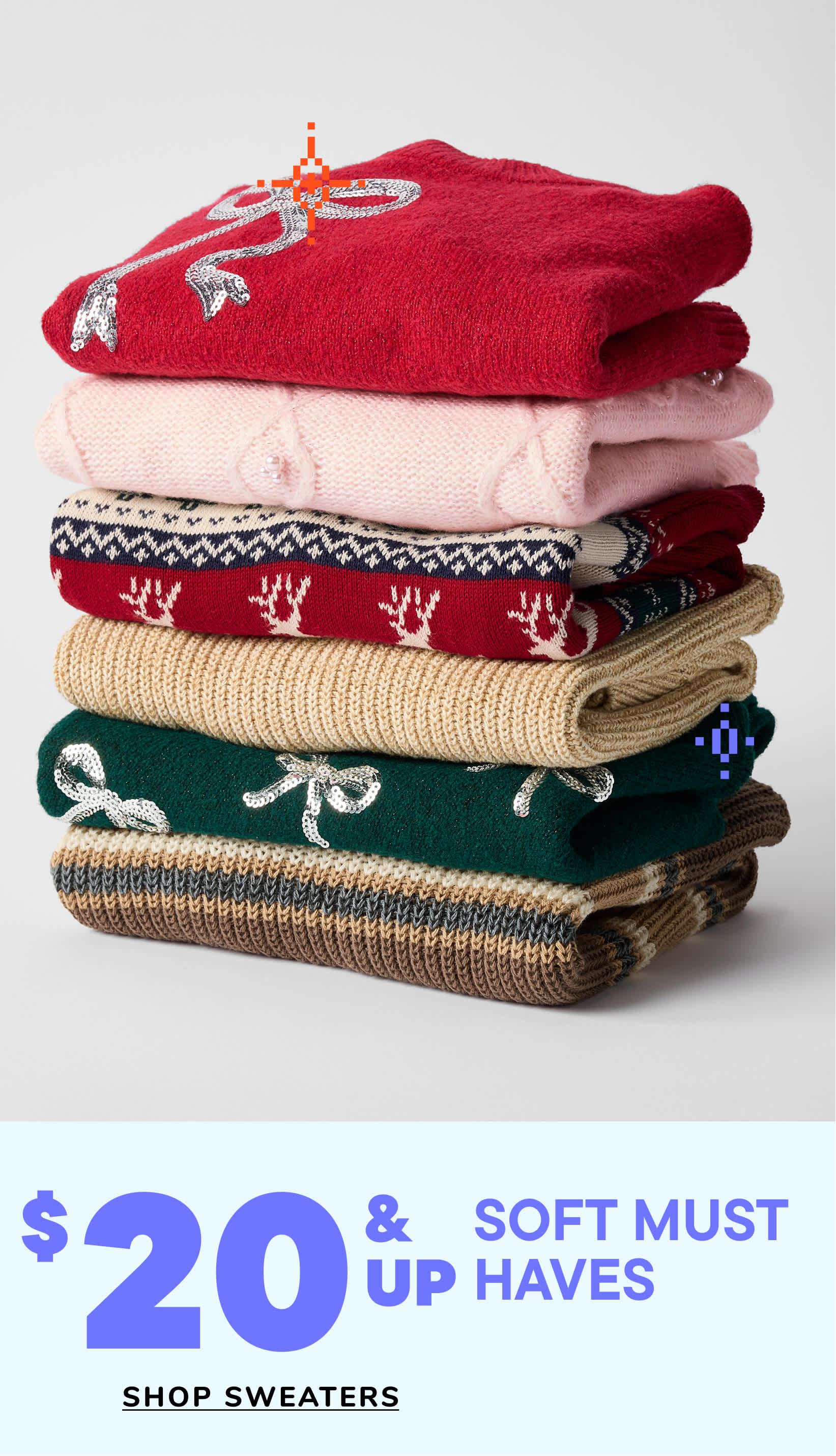 Two young girls with long, curly hair are holding hands and smiling while wearing denim jeans and light blue sweaters. The background is a plain white studio setting.