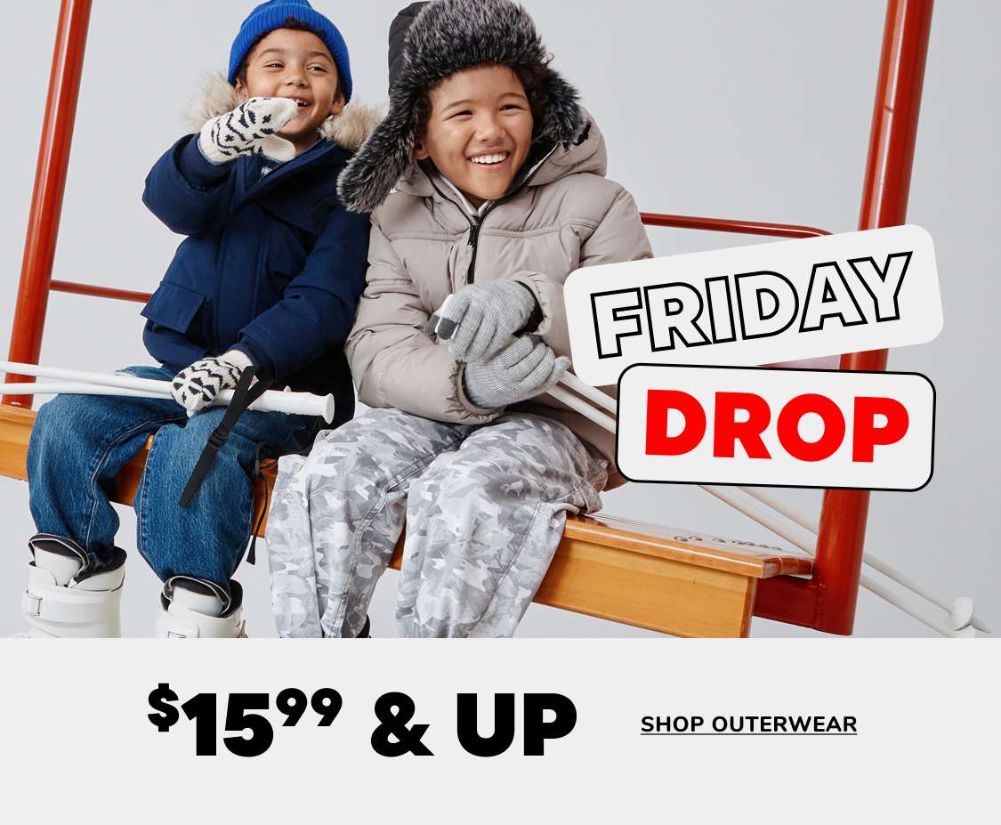 Two people, a young boy and girl, are sitting on a bench and smiling while wearing winter clothing. The background includes a sign advertising a "Friday Drop" sale with 60-70% off outerwear.