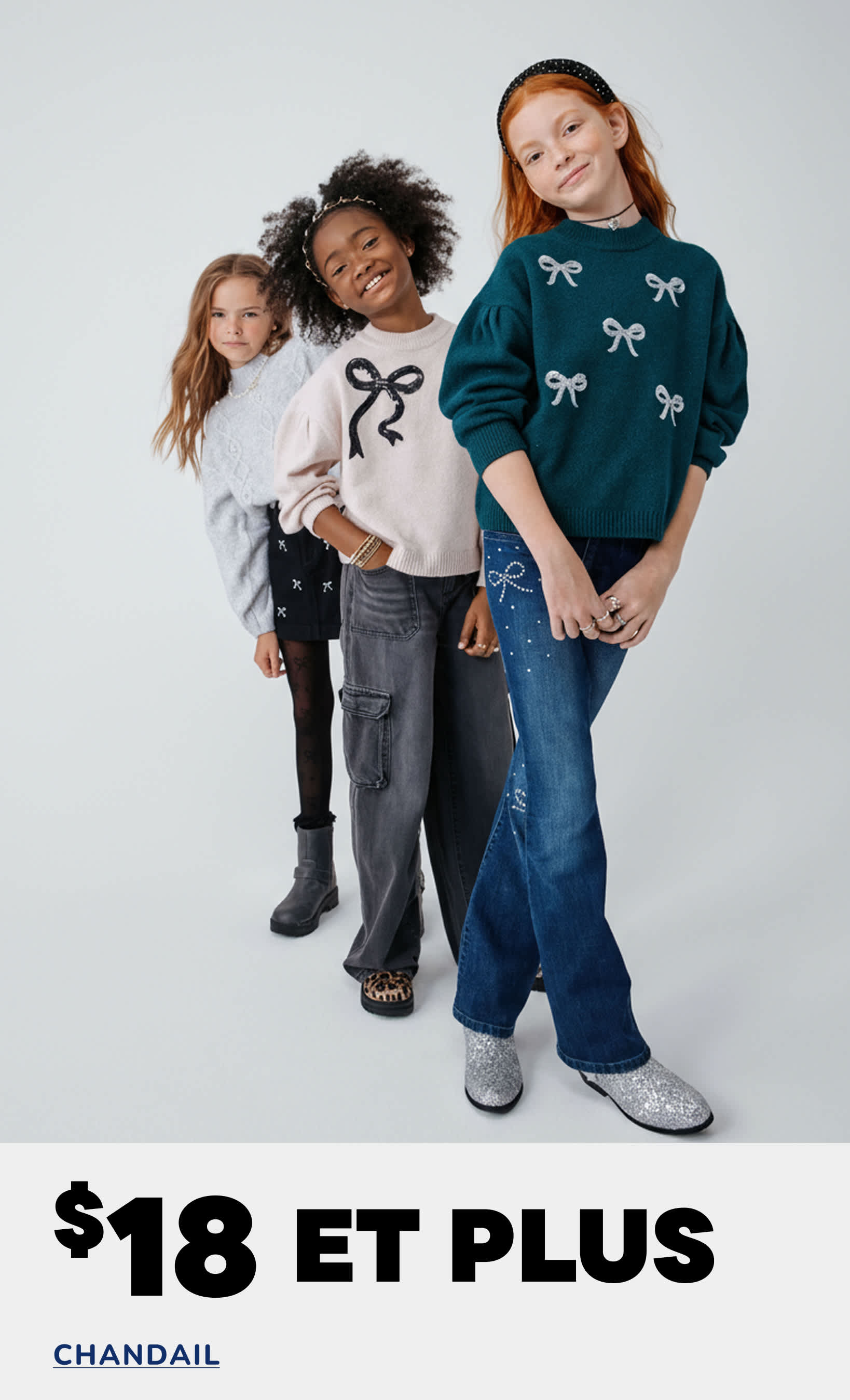 Trois jeunes filles vêtues de pulls et de jeans élégants posent ensemble dans un studio, avec un message promotionnel pour une vente de pulls affiché en arrière-plan.