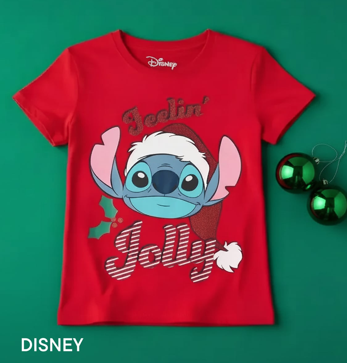 Un t-shirt rouge orné d'un dessin du personnage Disney Stitch sur fond vert uni, accompagné de décorations sur le thème de Noël.