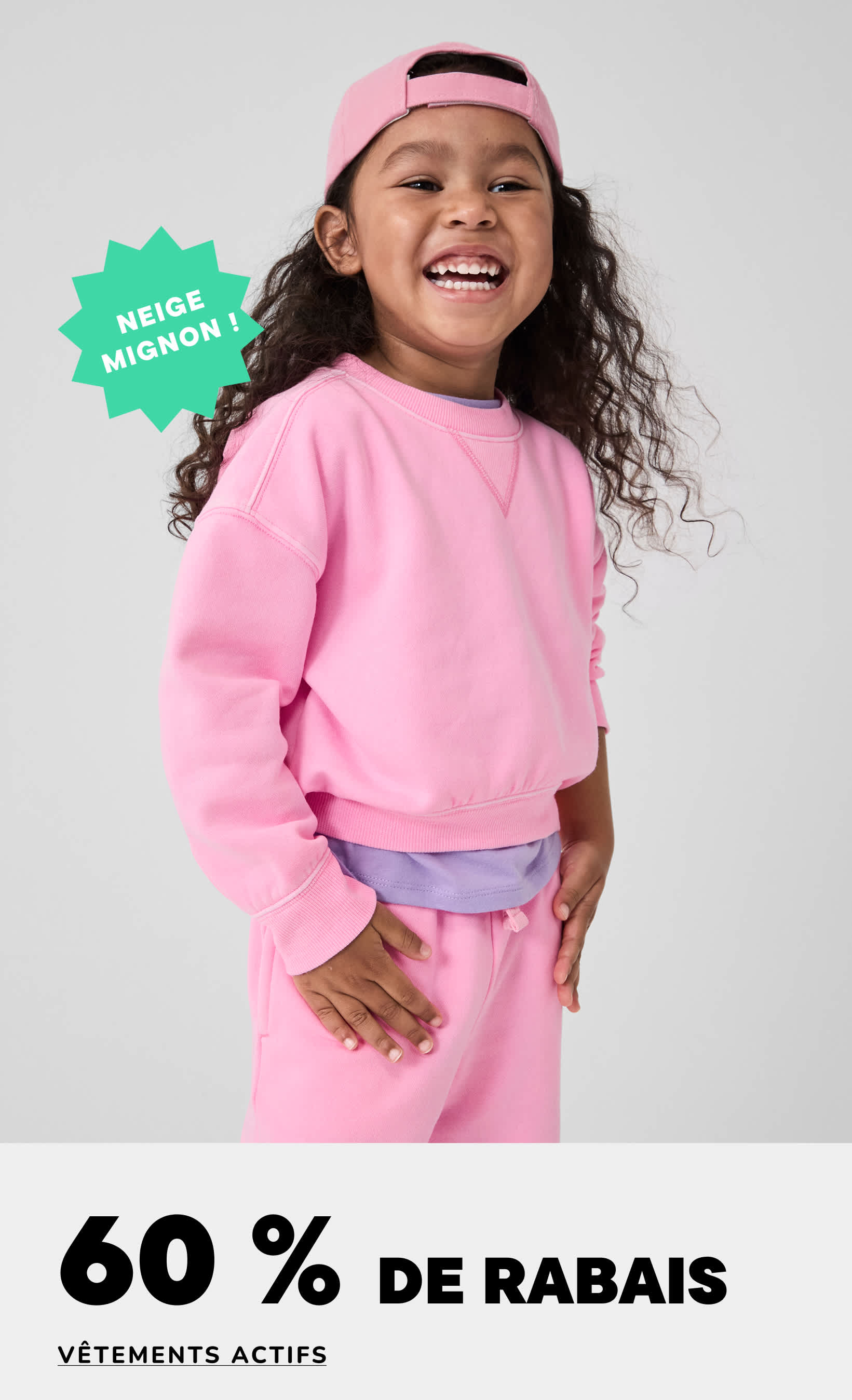 Une jeune fille aux cheveux bouclés, vêtue d'un sweat-shirt rose et d'un bandeau, sourit largement sur un fond blanc uni, avec la mention « 60 % de réduction » en surimpression.