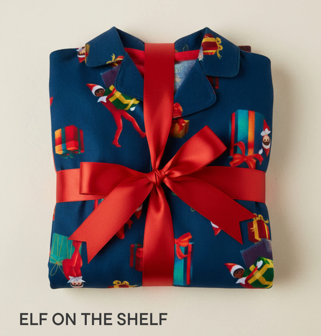 A neatly wrapped gift box with a red ribbon, featuring a festive pattern of elves and holiday decorations against a navy blue background.