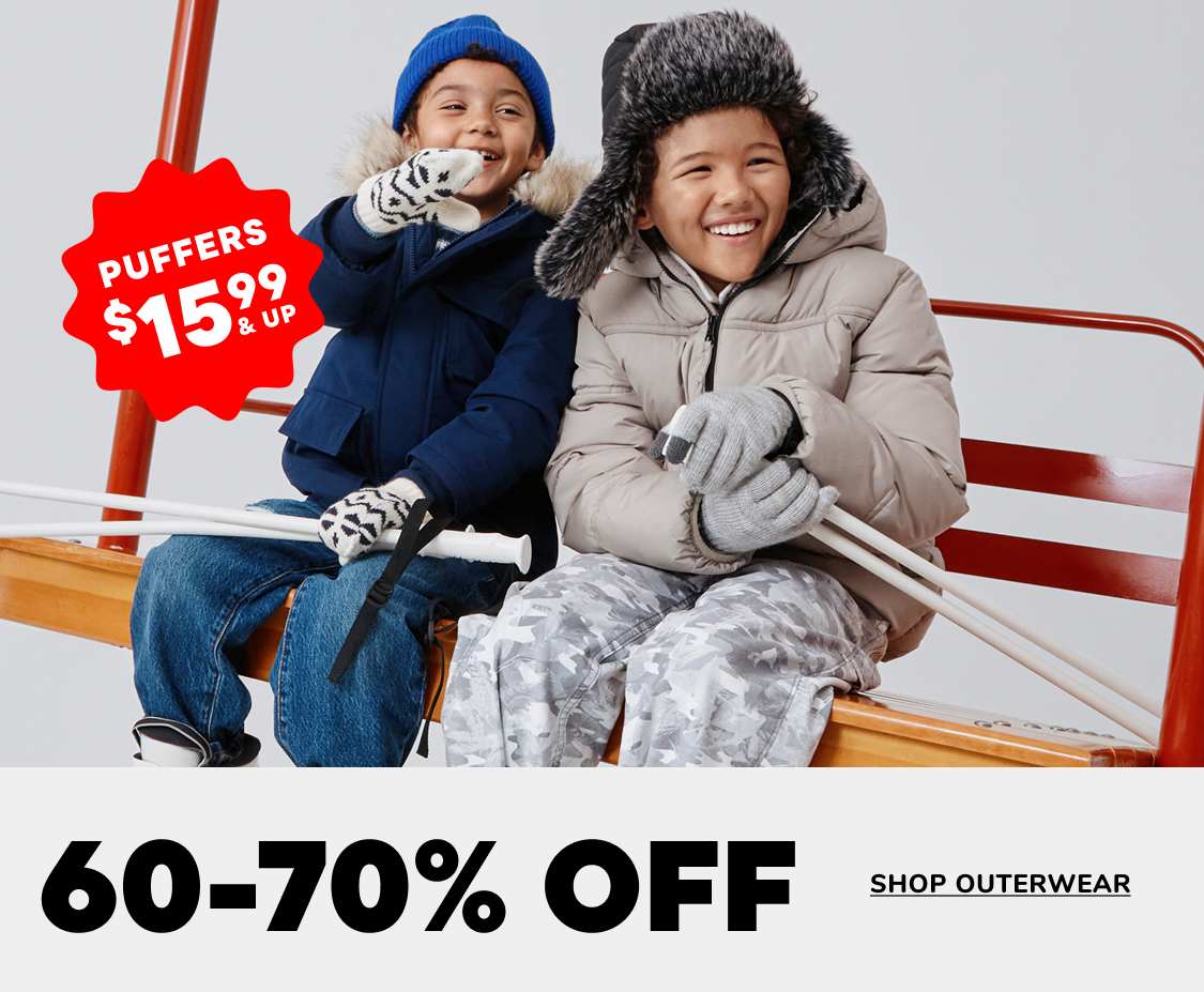 Two people, a young boy and girl, are sitting on a bench and smiling while wearing winter clothing. The background includes a sign advertising a "Friday Drop" sale with 60-70% off outerwear.