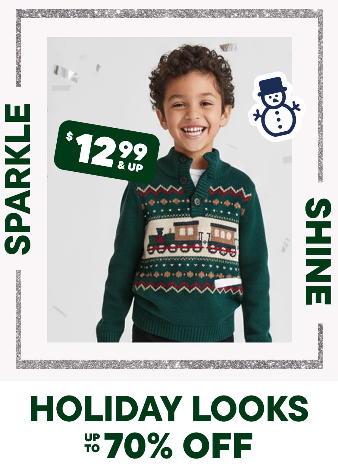 A young boy with curly hair is wearing a green and red patterned sweater and smiling at the camera, set against a background with a price tag and holiday-themed graphics.