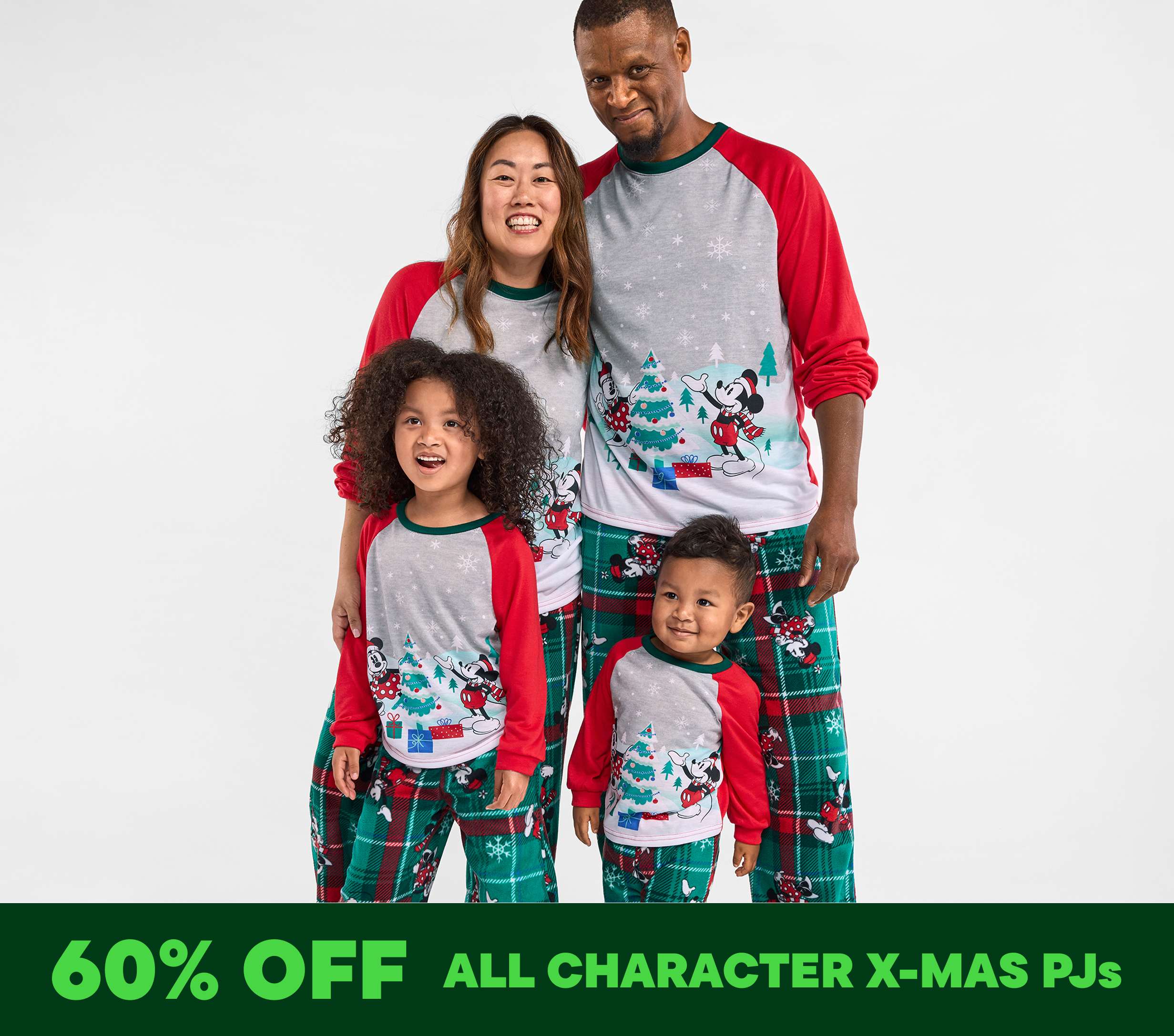 A happy family of four wearing matching Christmas-themed pajamas, posing together against a plain white background.