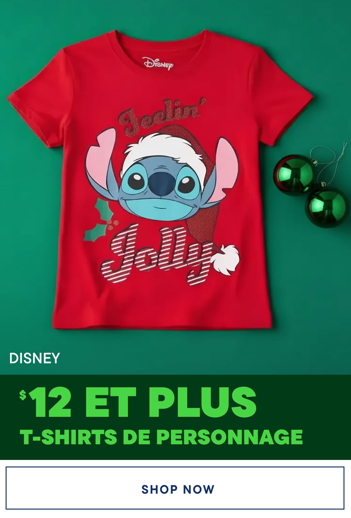 Un t-shirt rouge Disney représentant le personnage de Stitch portant un bonnet de Père Noël et l'inscription « Feelin' jolly » sur fond vert, avec des décorations de Noël vertes au premier plan.