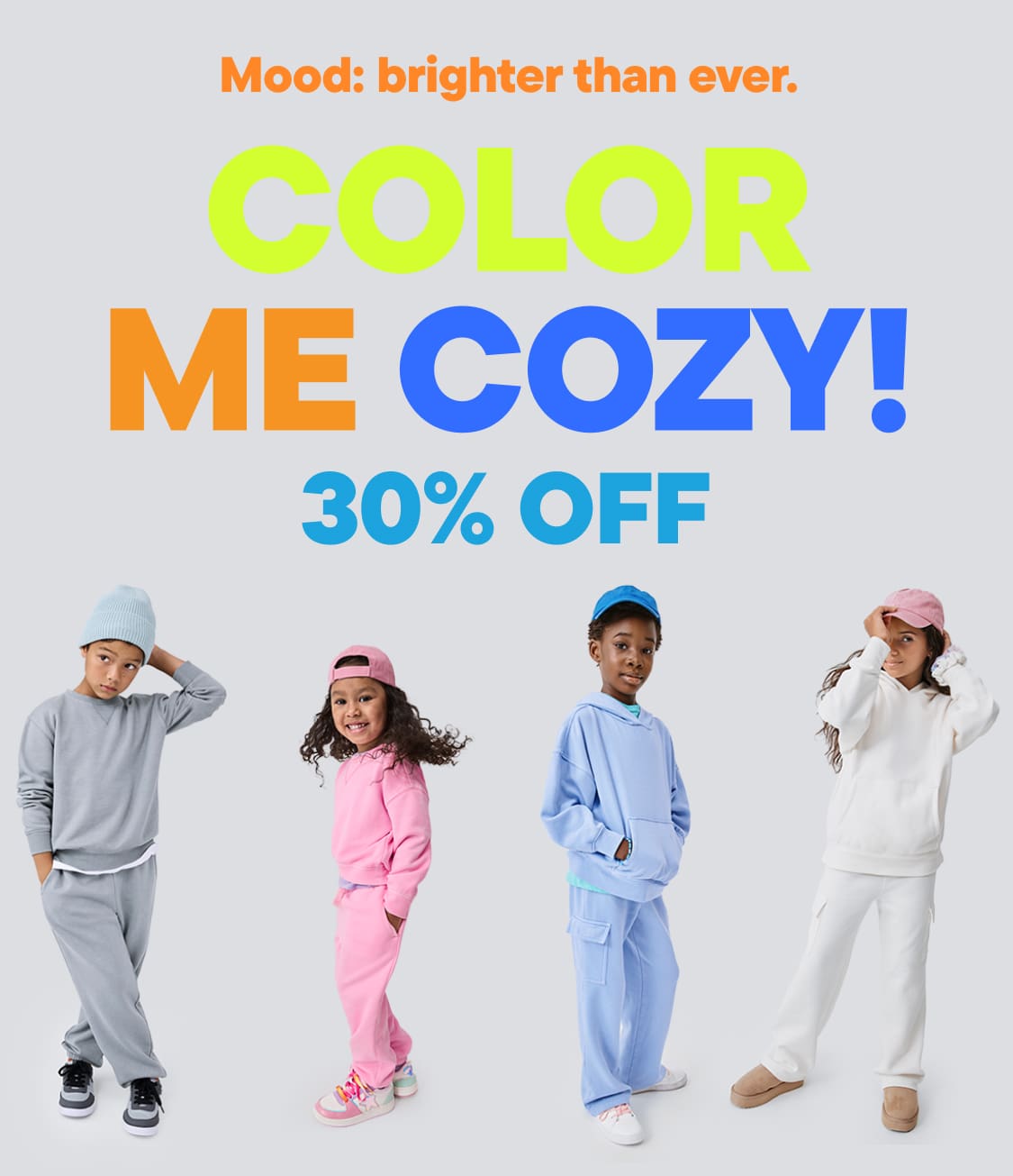 L'image présente deux personnes vêtues de tenues colorées et confortables sur un fond uni. Le texte superposé annonce une réduction de 30 % sur les produits « Color Me Cozy », avec le slogan « Humeur : plus joyeuse que jamais », soulignant le thème dynamique et gai.