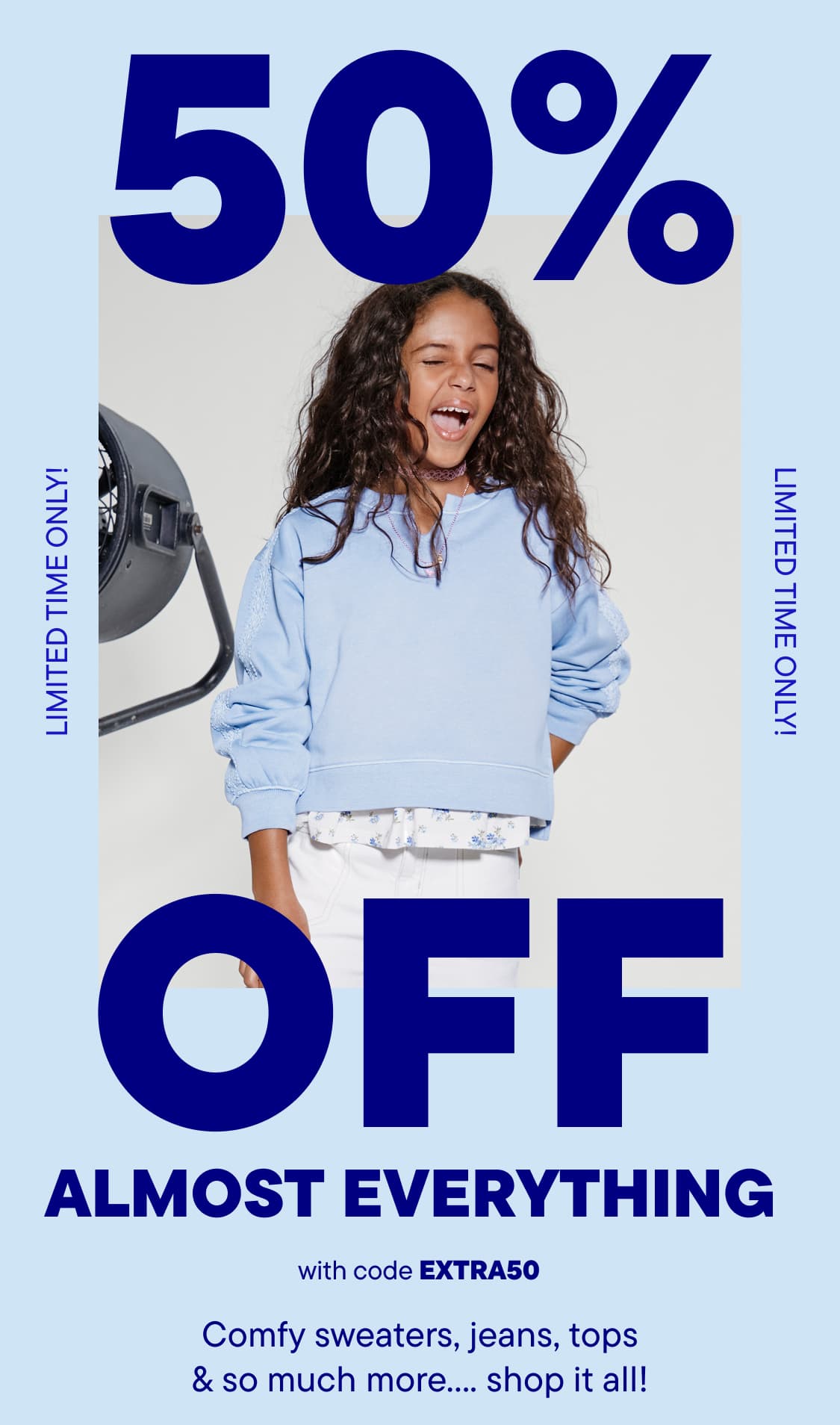 A smiling young boy wearing a white and blue striped shirt and a baseball cap stands in front of a large "50% OFF ALMOST EVERYTHING" advertisement.