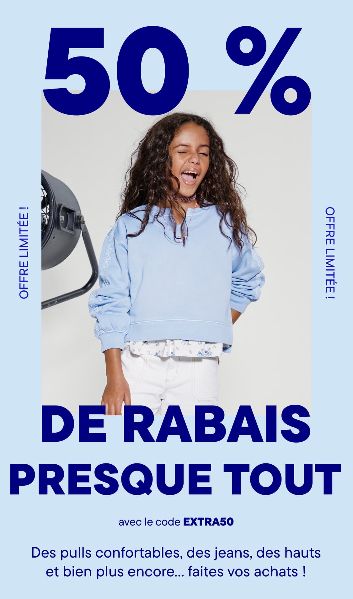 Un jeune garçon souriant, vêtu d'une chemise à rayures blanches et bleues et d'une casquette de baseball, se tient devant une grande affiche publicitaire annonçant « 50 % de réduction sur presque tout ».