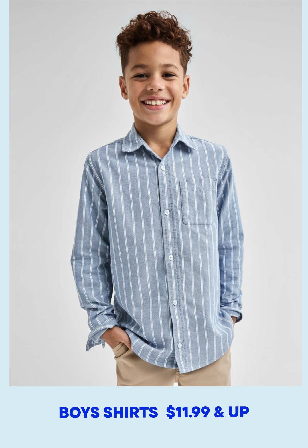 A young boy with curly hair is smiling while wearing a striped button-up shirt against a plain white background.