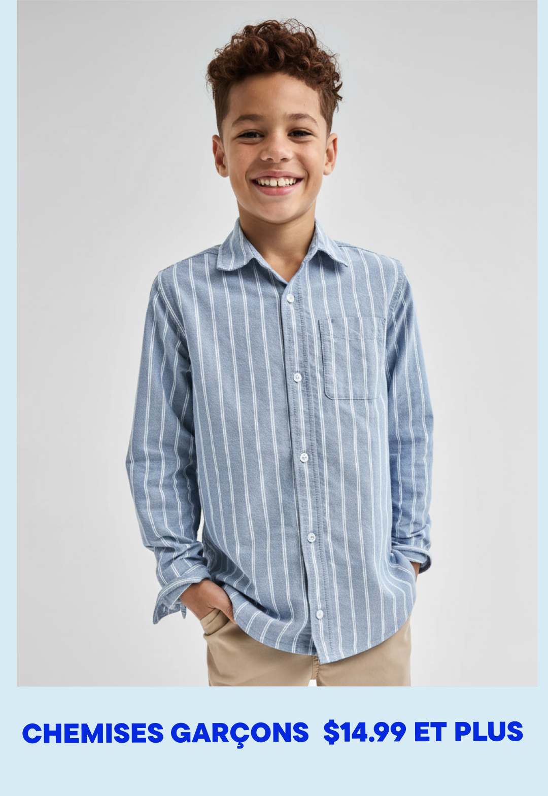 Un jeune garçon aux cheveux bouclés sourit, vêtu d'une chemise rayée boutonnée, sur un fond blanc uni.