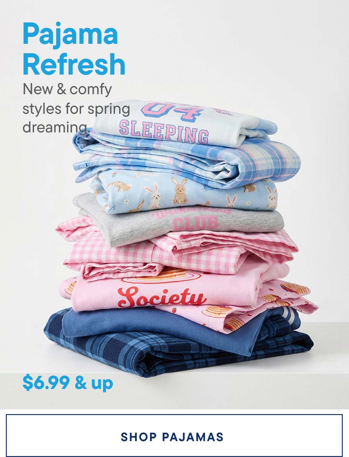A stack of colorful and patterned pajamas, including blue and pink designs, with text such as "Sleeping" and "Society" visible, against a plain white background.