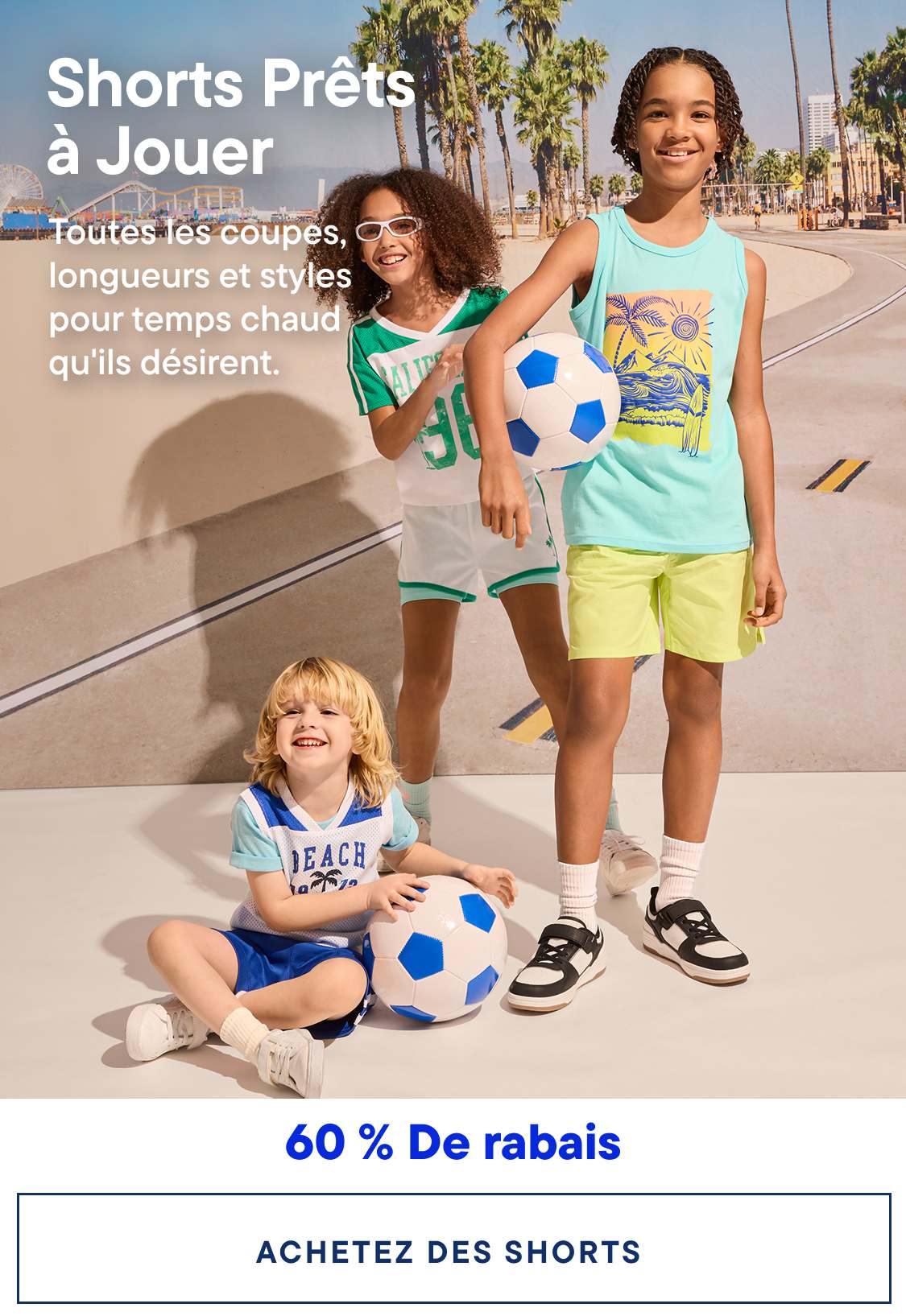 Trois enfants en tenue d'été décontractée, deux tenant des ballons de football, posent devant un arrière-plan flou de palmiers et d'une scène de rue.