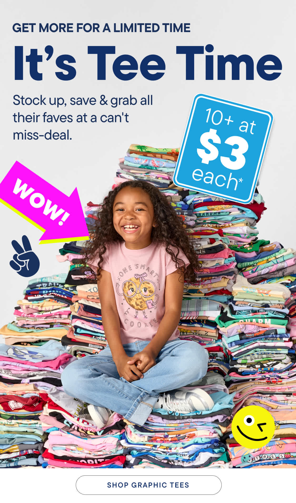 A young girl sits cross-legged on a large pile of colorful t-shirts, with a "WOW!" graphic and a smiley face in the background.