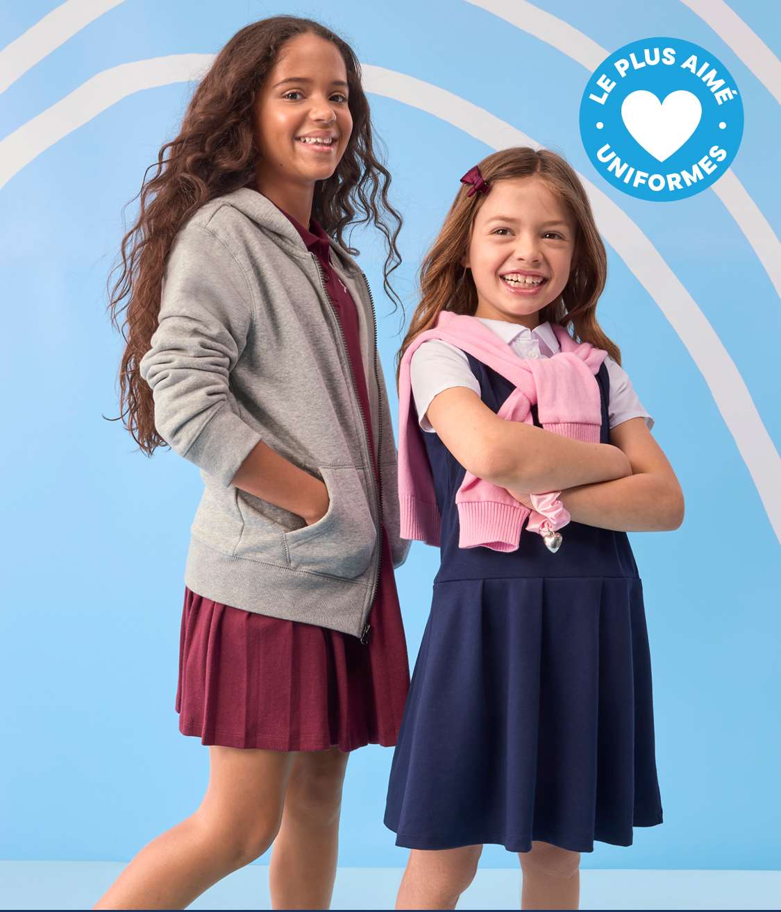 Deux jeunes filles souriantes en uniforme scolaire se détachent sur un fond bleu clair orné d'arches blanches.