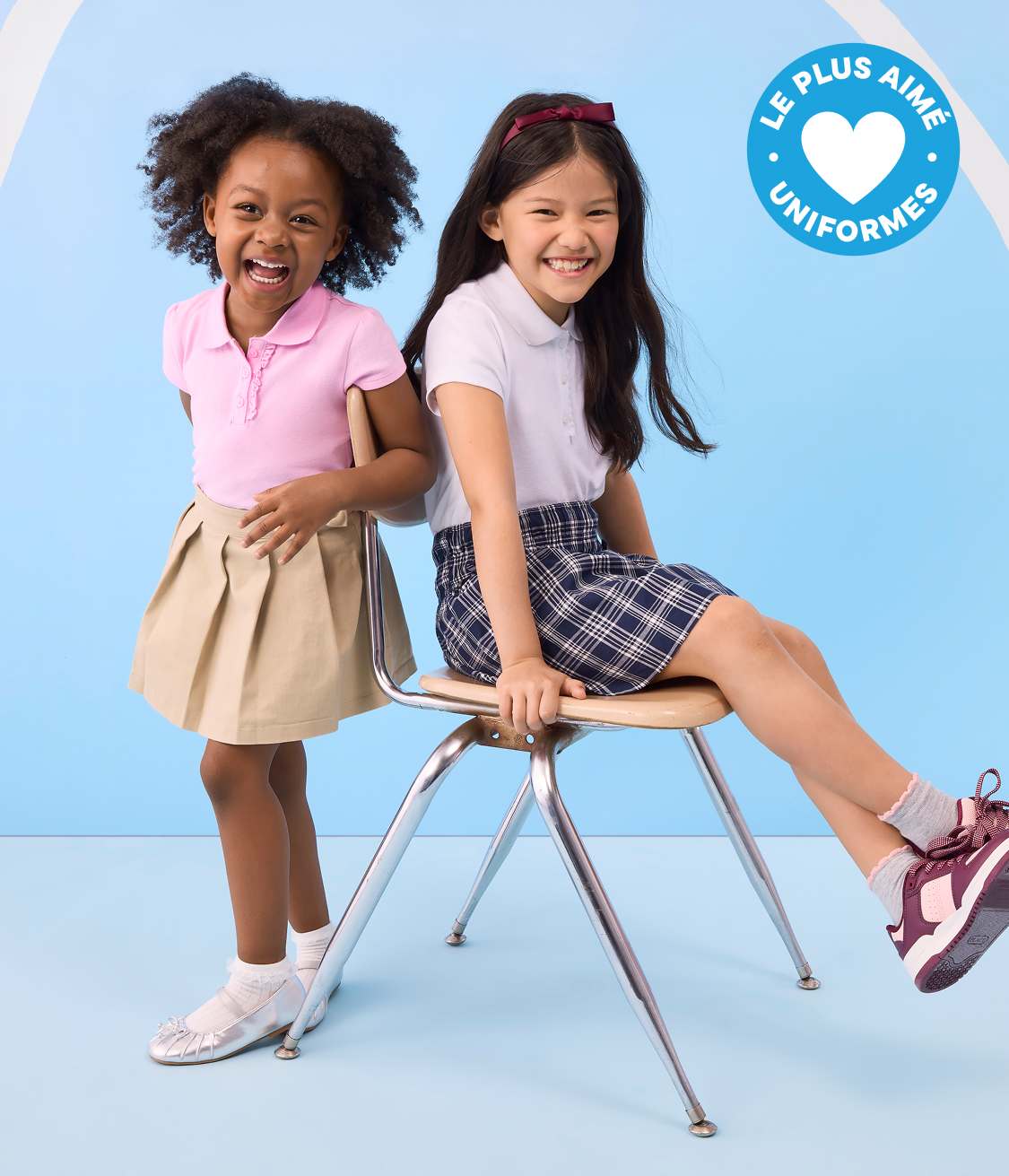 Deux jeunes filles en uniforme scolaire sourient devant un fond bleu clair orné d'un badge « Uniformes préférés ».