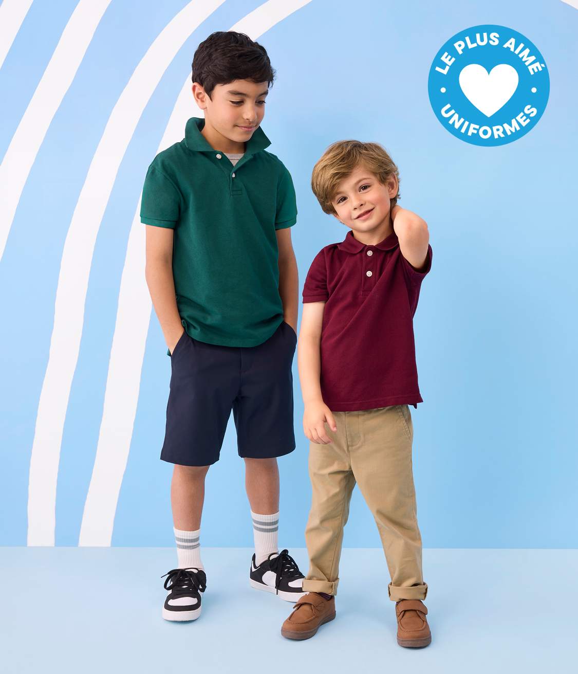 Deux jeunes garçons en uniforme scolaire se tiennent sur un fond bleu clair à rayures blanches ondulées, avec un badge « Uniformes préférés » dans le coin supérieur droit.