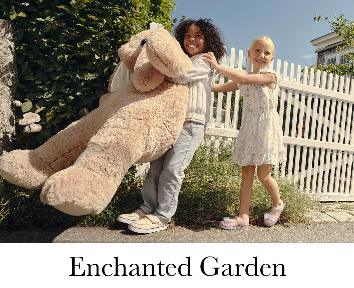 Une Coccinelle Volkswagen bleu clair vintage garée dans un jardin luxuriant et verdoyant, avec deux jeunes femmes vêtues de tenues fluides de style bohème se tenant à côté de la voiture.
