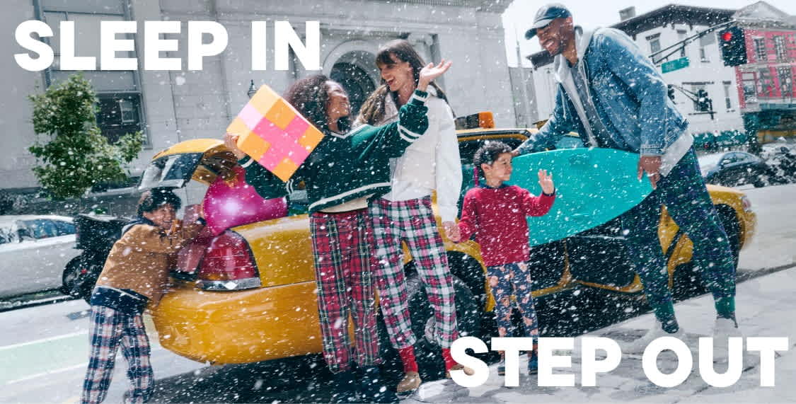 A group of people in colorful, patterned clothing stand in the snow, holding various objects and appearing to be engaged in some kind of festive or celebratory activity.