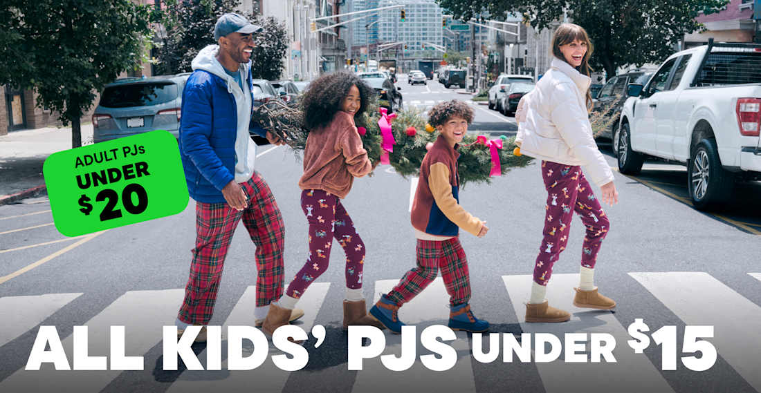 The image shows a group of people, likely friends or family, standing on a city street. They are wearing colorful, patterned clothing and appear to be shopping or browsing at a nearby store, as indicated by the price tags and signs in the foreground.