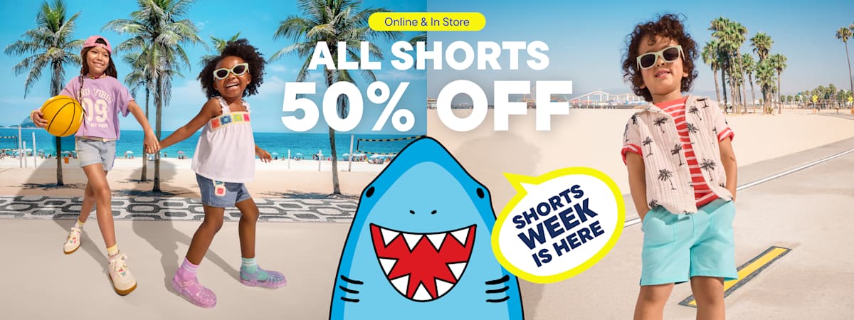 The image features two young people wearing colorful, stylish summer outfits standing in front of a tropical beach scene, with a large sign advertising a 50% off sale on all shorts.