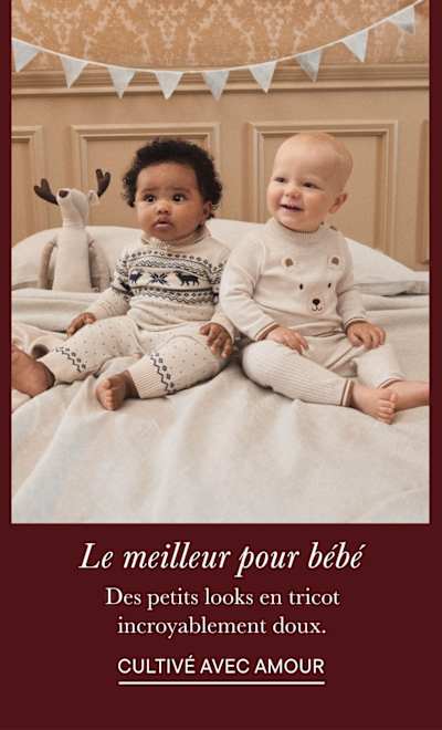 Deux jeunes enfants, un garçon et une fille, assis sur un lit entourés de décorations festives et d'une atmosphère chaleureuse et familiale.